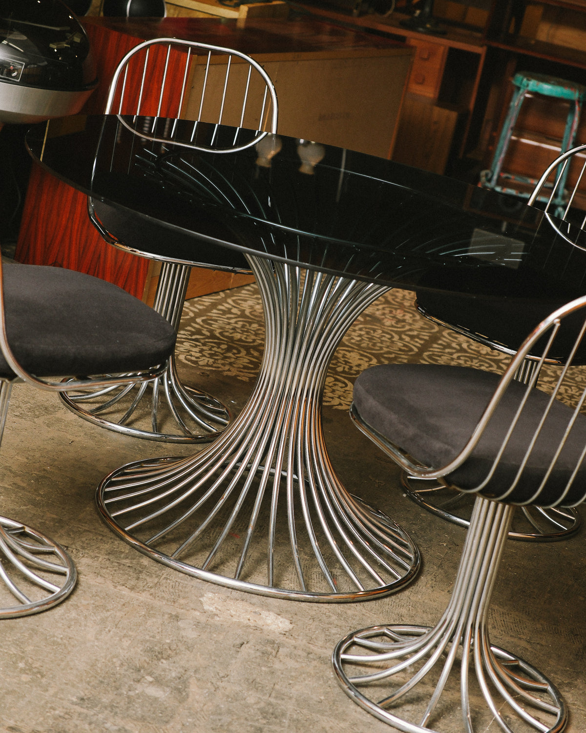 Close angle on the radiating chrome pedestal base beneath the oval glass table top.