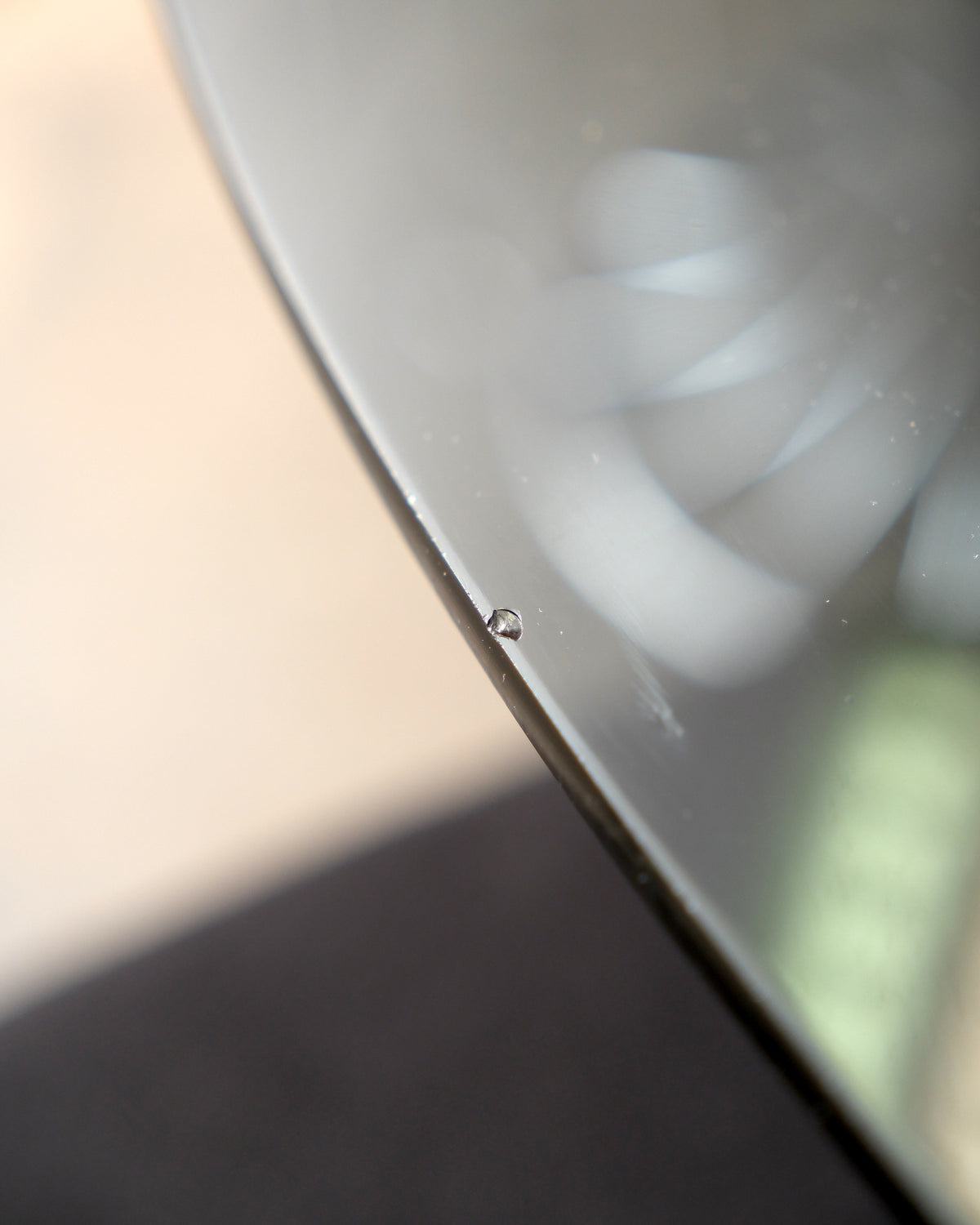 Close-up of a small chip on the edge of the glass table top.