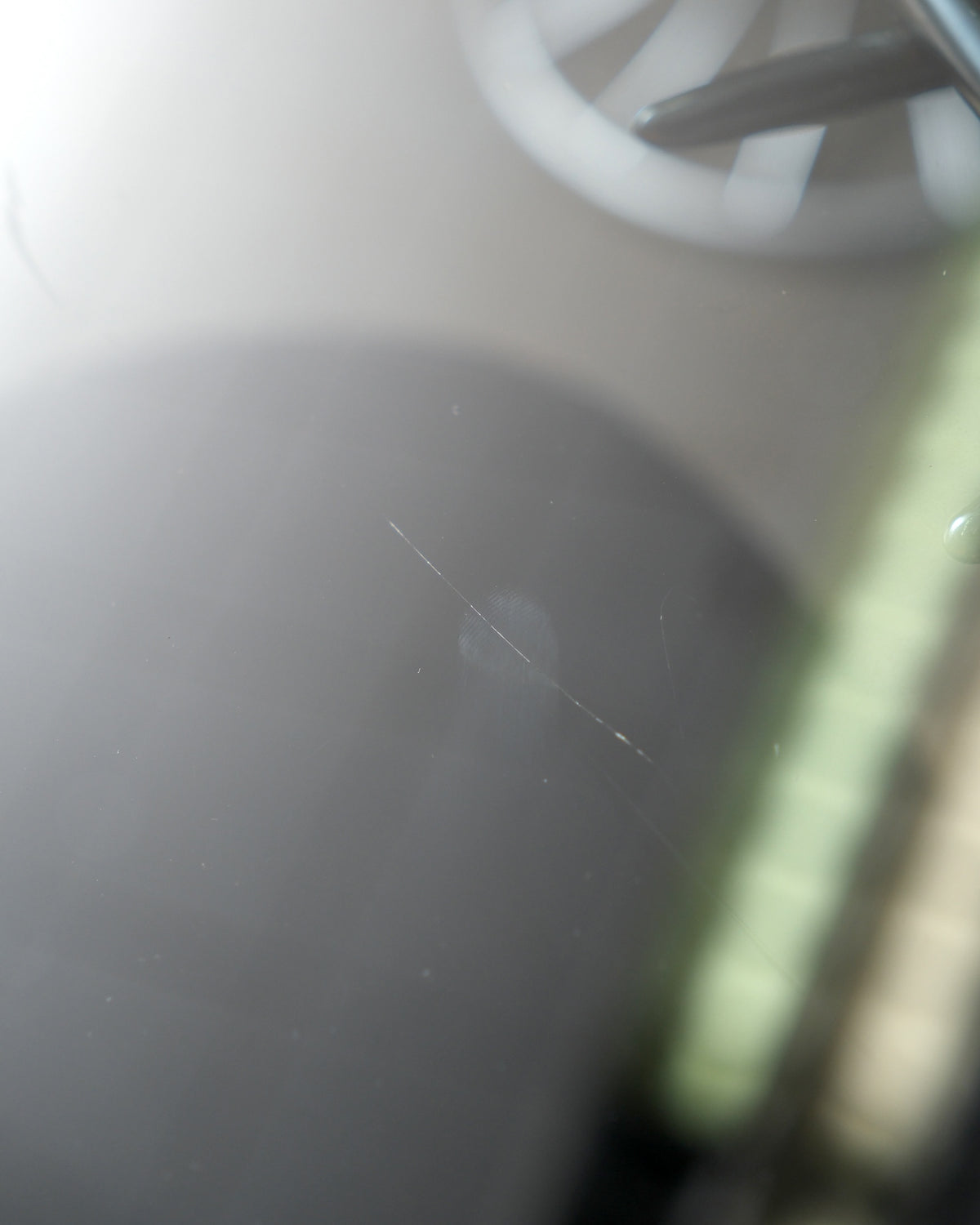 Close-up of a faint scratch on the glass table top surface.