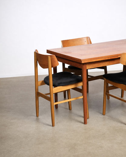 Wide shot of the full dining set in the showroom with other vintage furniture visible.