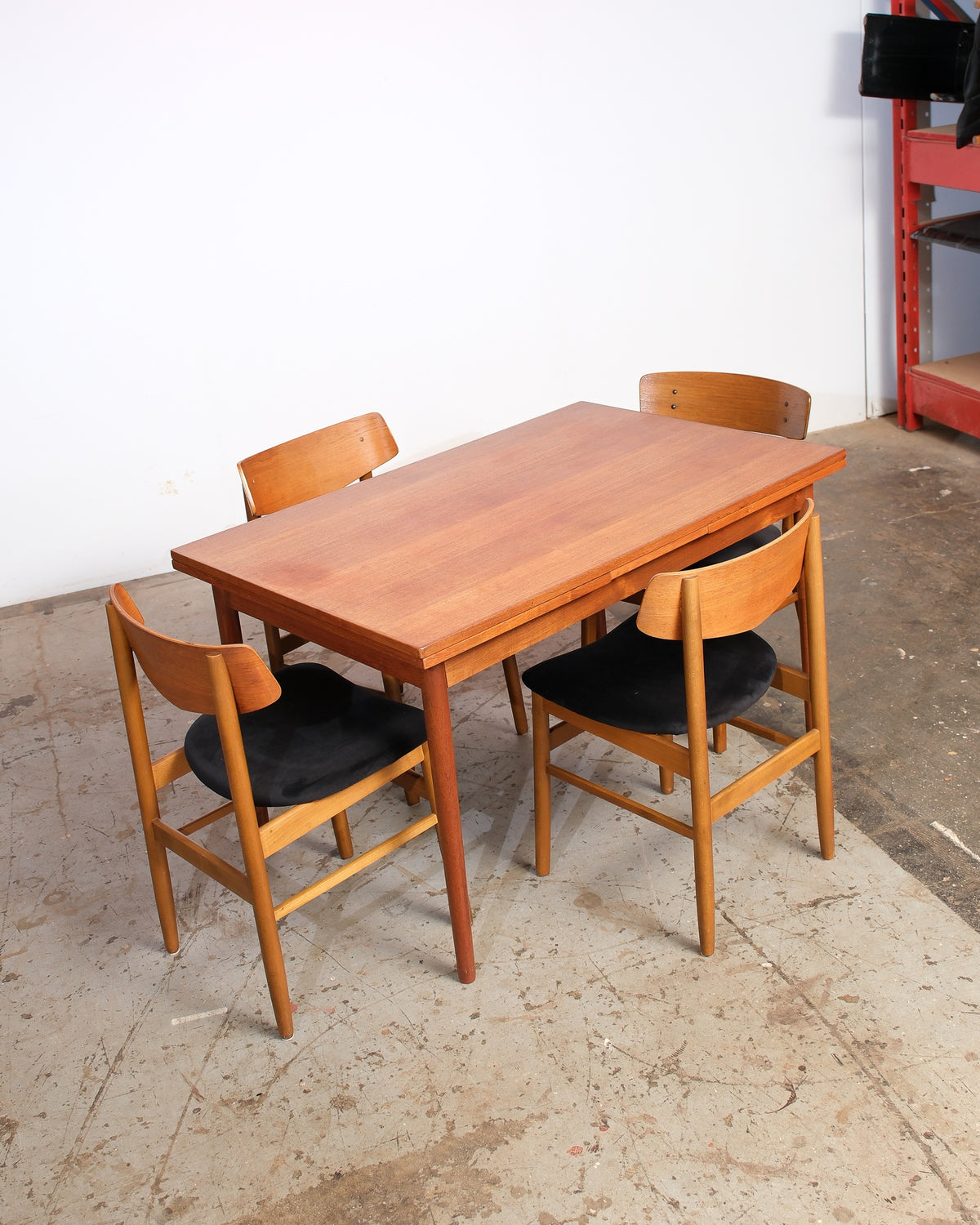 Full view of the teak dining table with four chairs arranged around it.
