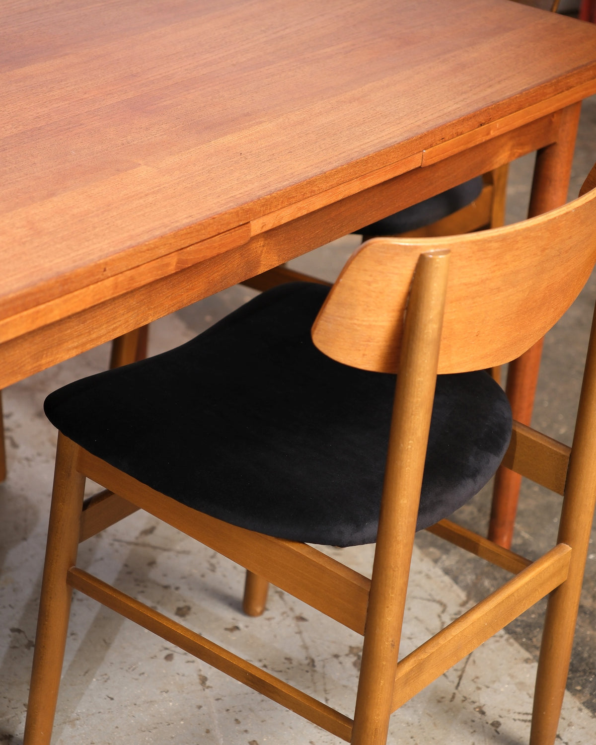 Detail of the table's extendable top edge and a chair's bentwood back and black seat.