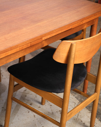 Detail of the table's extendable top edge and a chair's bentwood back and black seat.