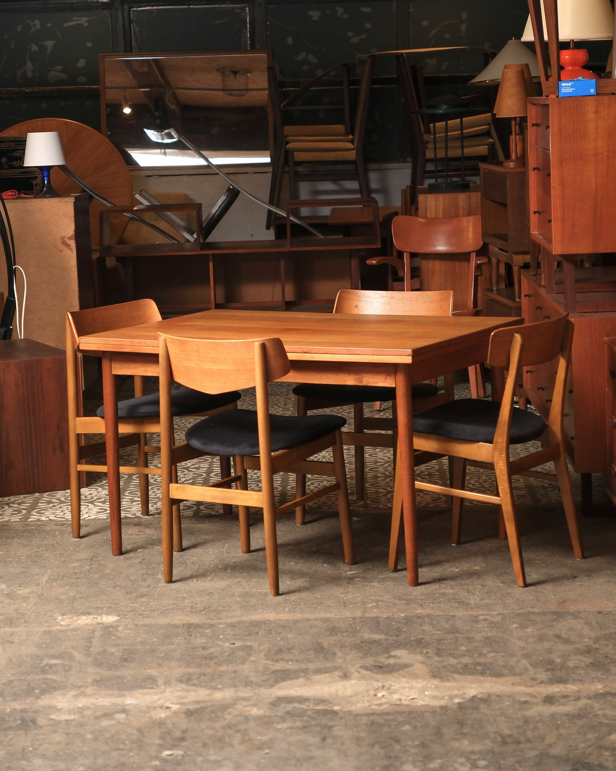 Dining set staged in a vintage furniture showroom surrounded by other mid-century pieces.