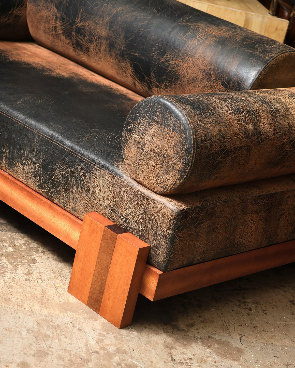 Close-up of the sofa's corner joinery, wood base, and striped block foot detail.