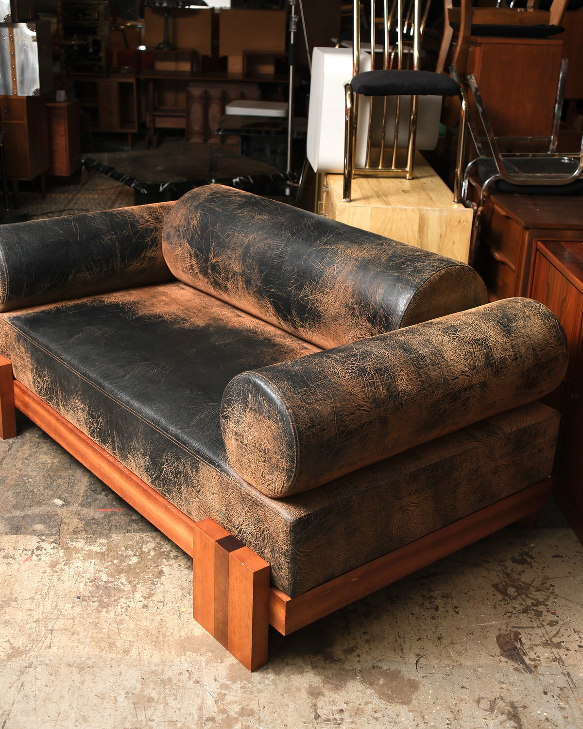Angled close-up view of the distressed leather sofa's bolster back and seat cushion.