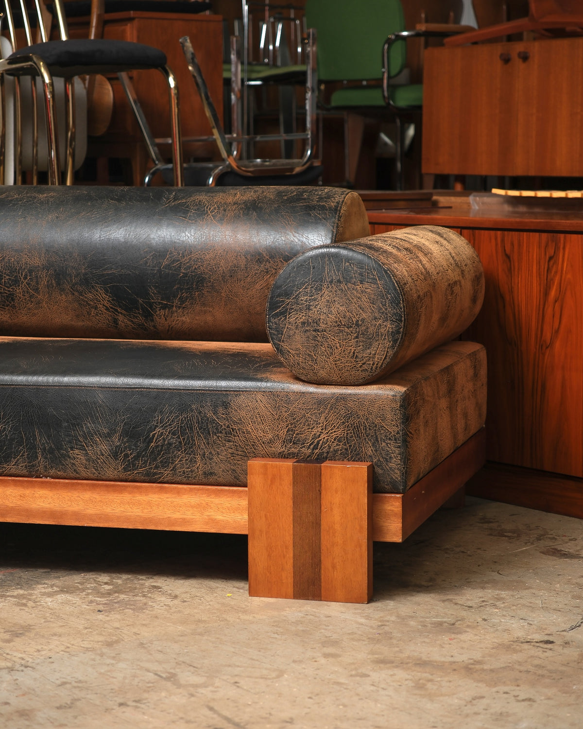 Detail of a bolster arm and wood block foot on the distressed leather sofa.