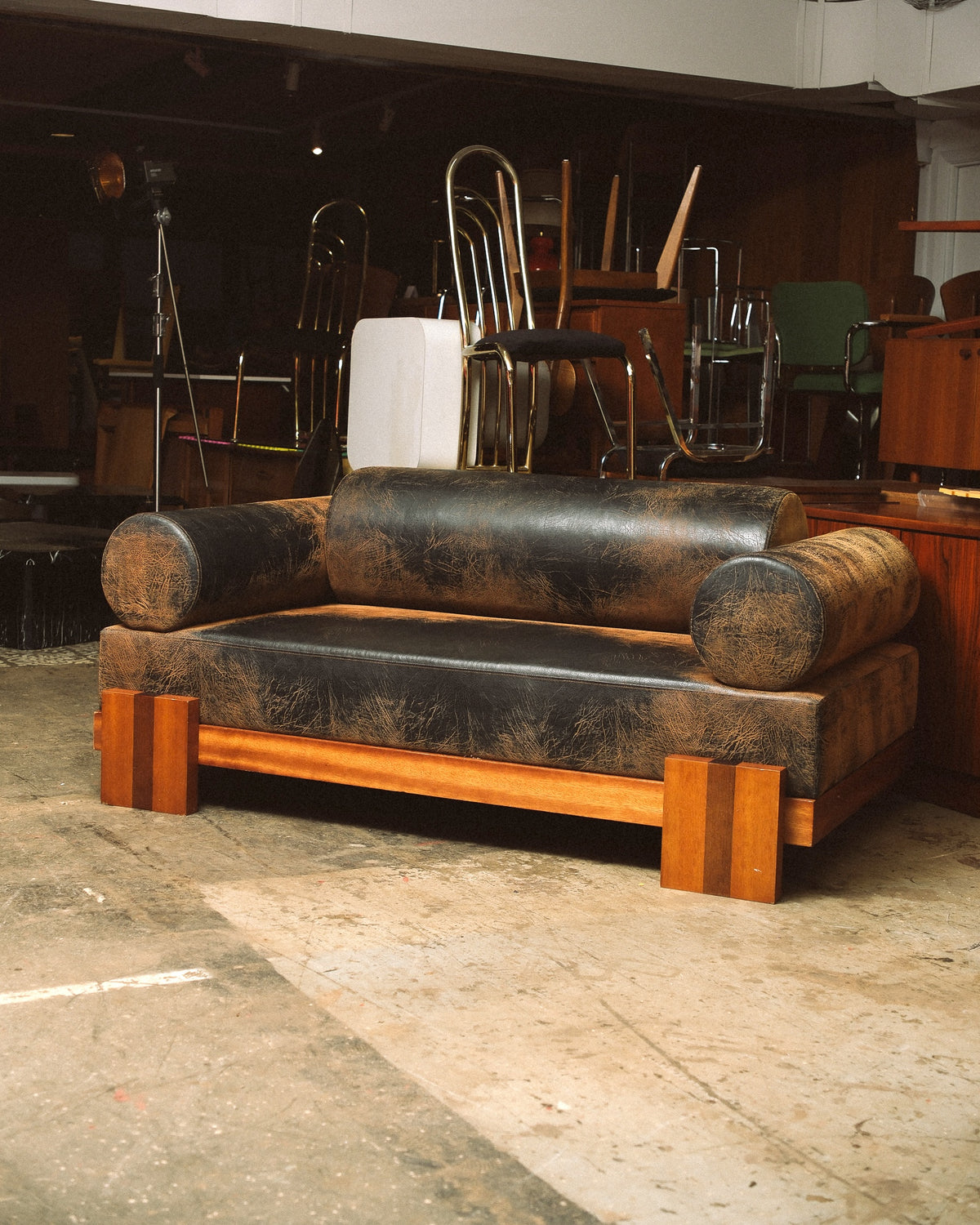 Front view of the distressed leather sofa in a warmly lit showroom setting.