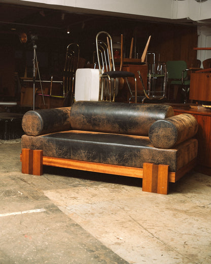 Front view of the distressed leather sofa in a warmly lit showroom setting.