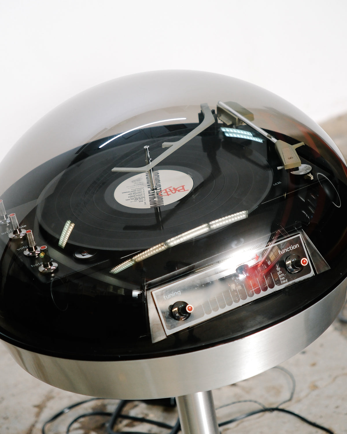 Overhead view of the Electrohome 711 Saturn turntable under its polished plexiglass dome, showing the tonearm and control