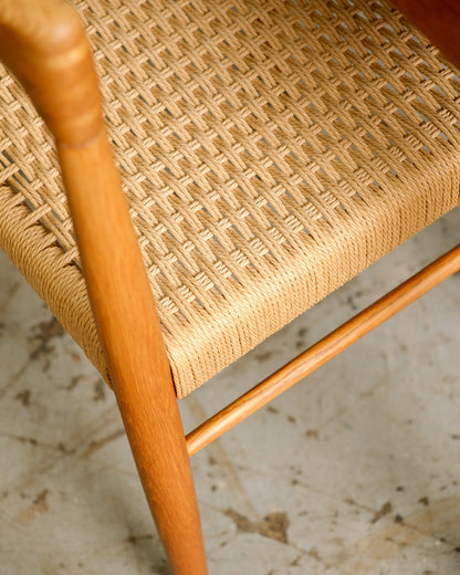 Detail of a chair's woven cord seat and oak frame joinery, seen from above.