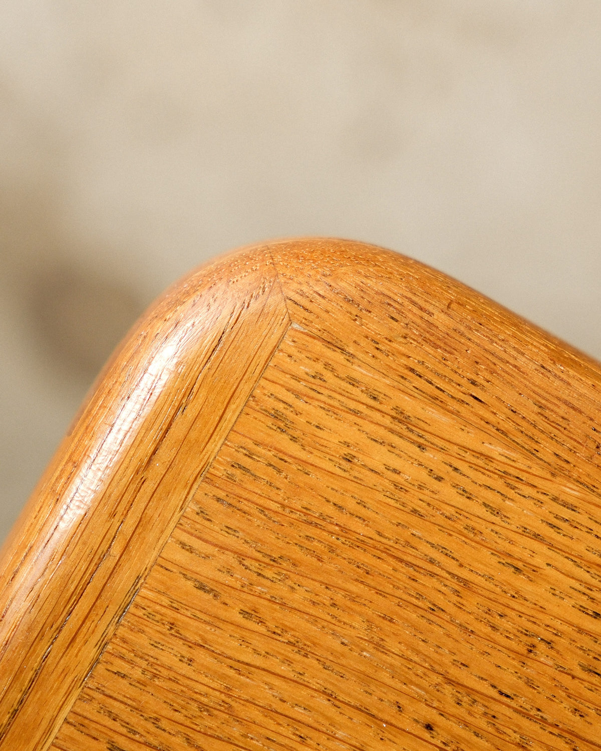 Close-up of the oak table's edge and mitred corner joinery, showing wood grain.
