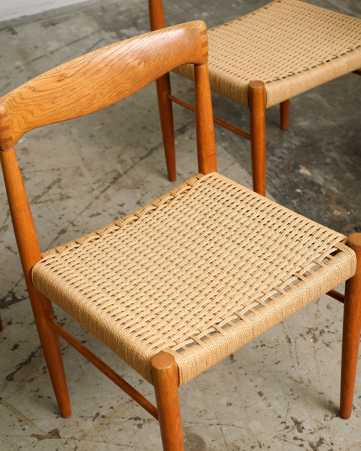 Overhead view of two chairs' woven cord seats and oak frames side by side.