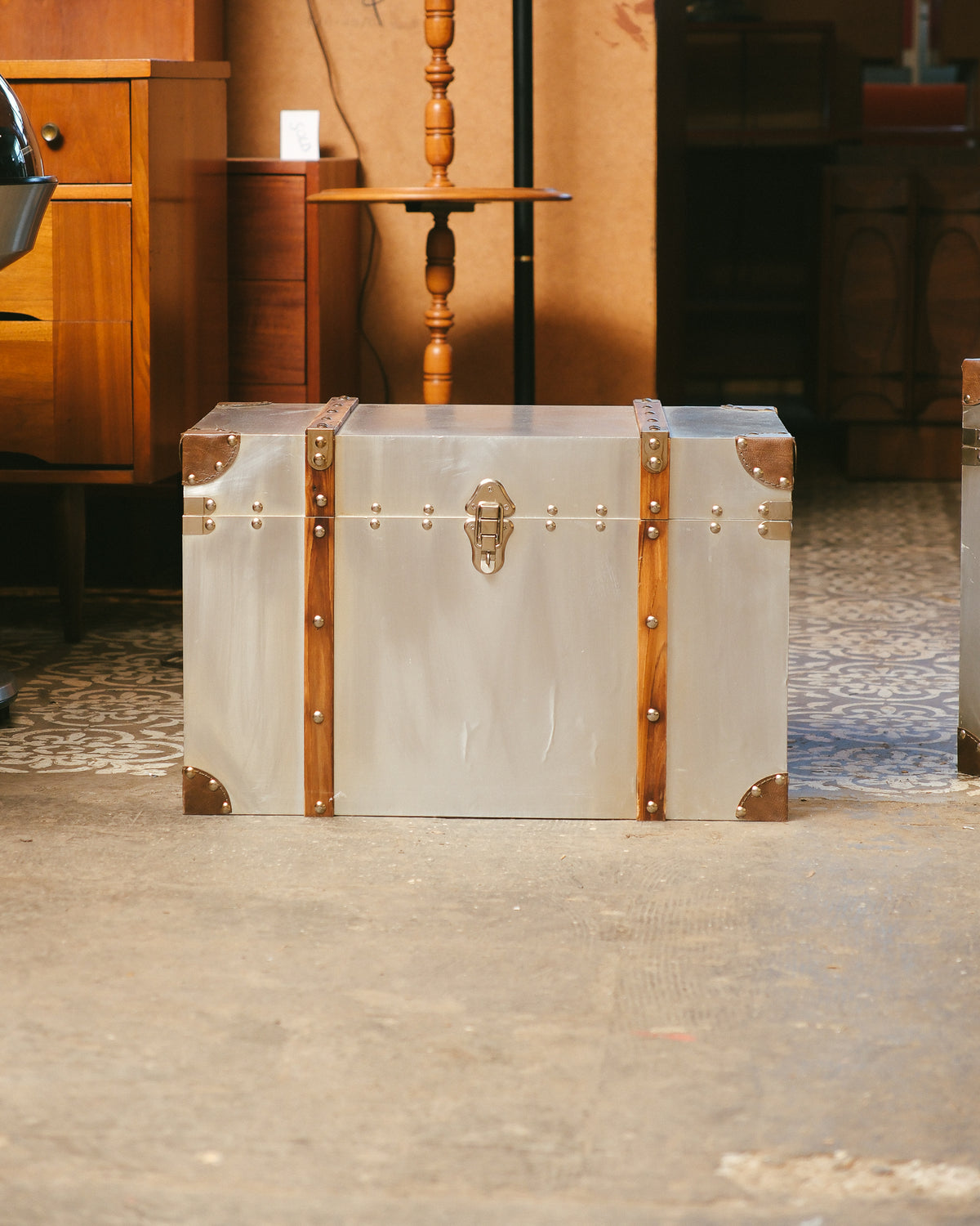 Straight-on front view of the large trunk showing the centered latch, wood strapping, and leather corners.