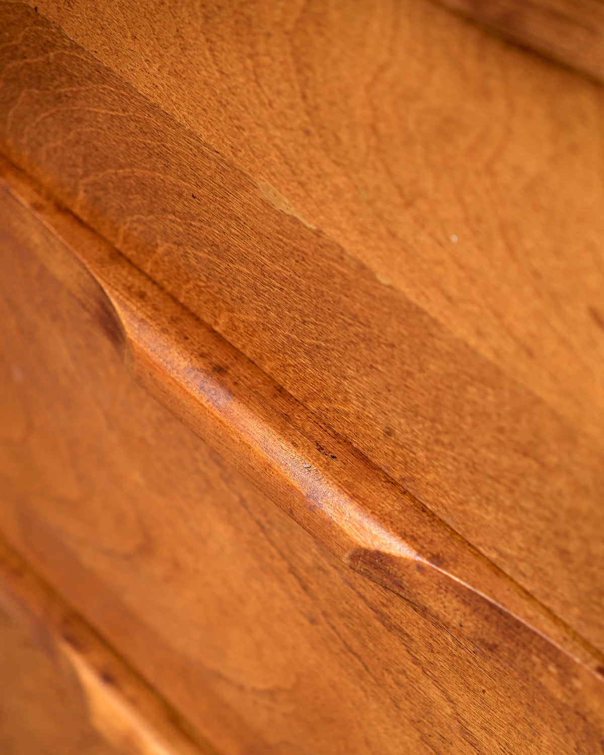 Close-up of a drawer front showing wood grain and a small surface ding.