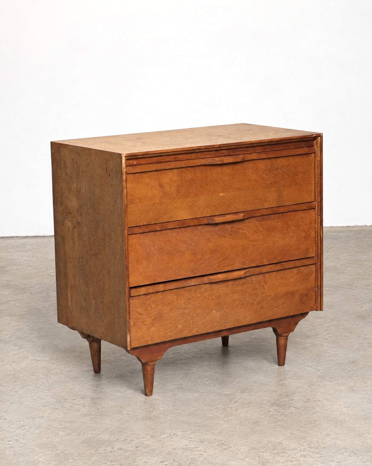 Angled side view of the dresser showing depth, legs, and carved apron detail.