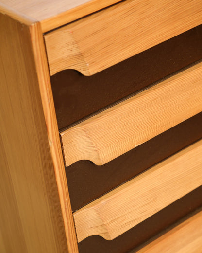 Close-up of sculpted wood drawer pulls showing grain detail and joinery on a mid-century dresser