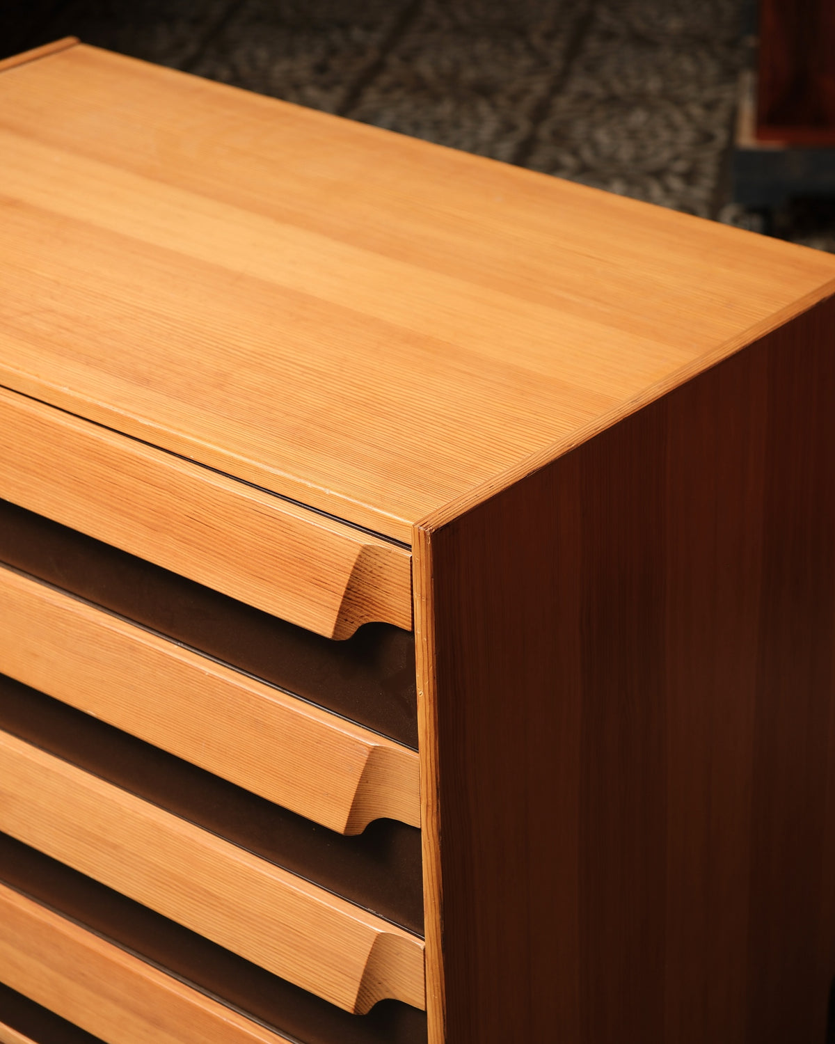 Close-up of the top corner showing wood grain, drawer pulls, and case joinery