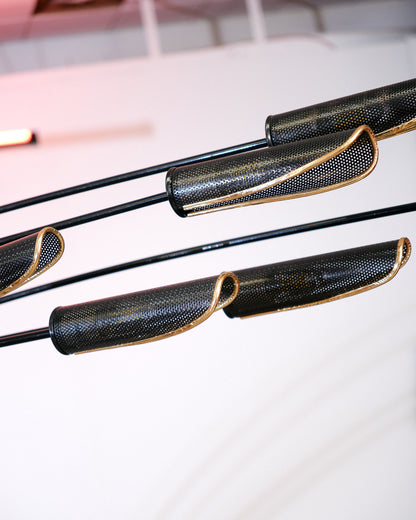 Close-up of the perforated metal shades with brass edging on the black floor lamp's arms.