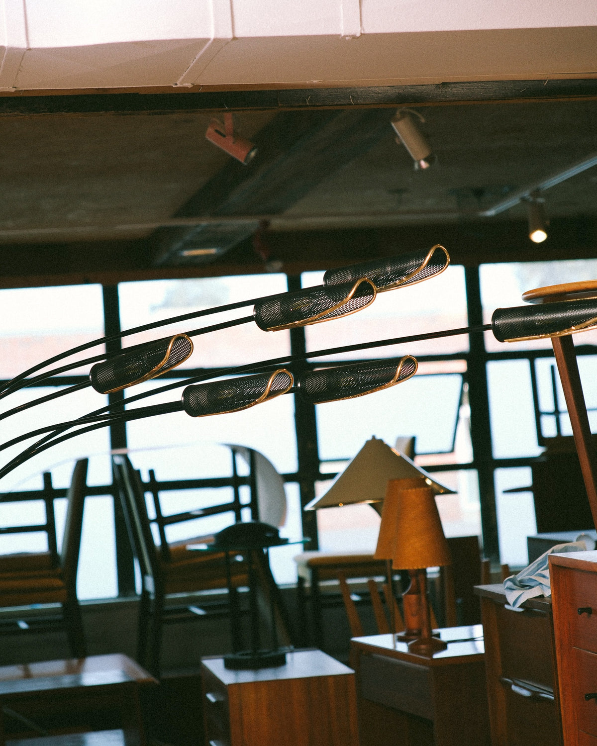 The floor lamp's arched arms and shades shown against a showroom backdrop of vintage furniture.