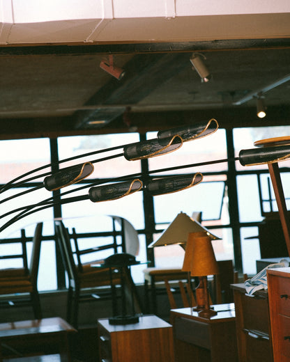 The floor lamp's arched arms and shades shown against a showroom backdrop of vintage furniture.
