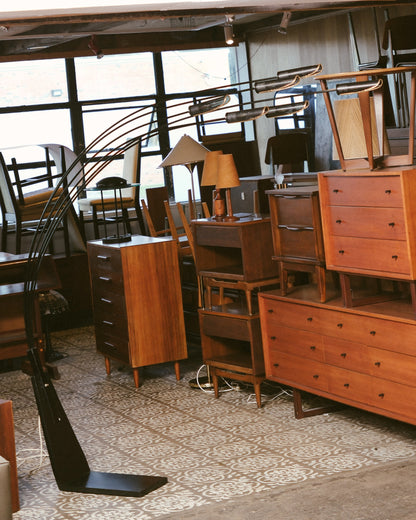 Wide view of the showroom with the floor lamp standing among other mid-century pieces.
