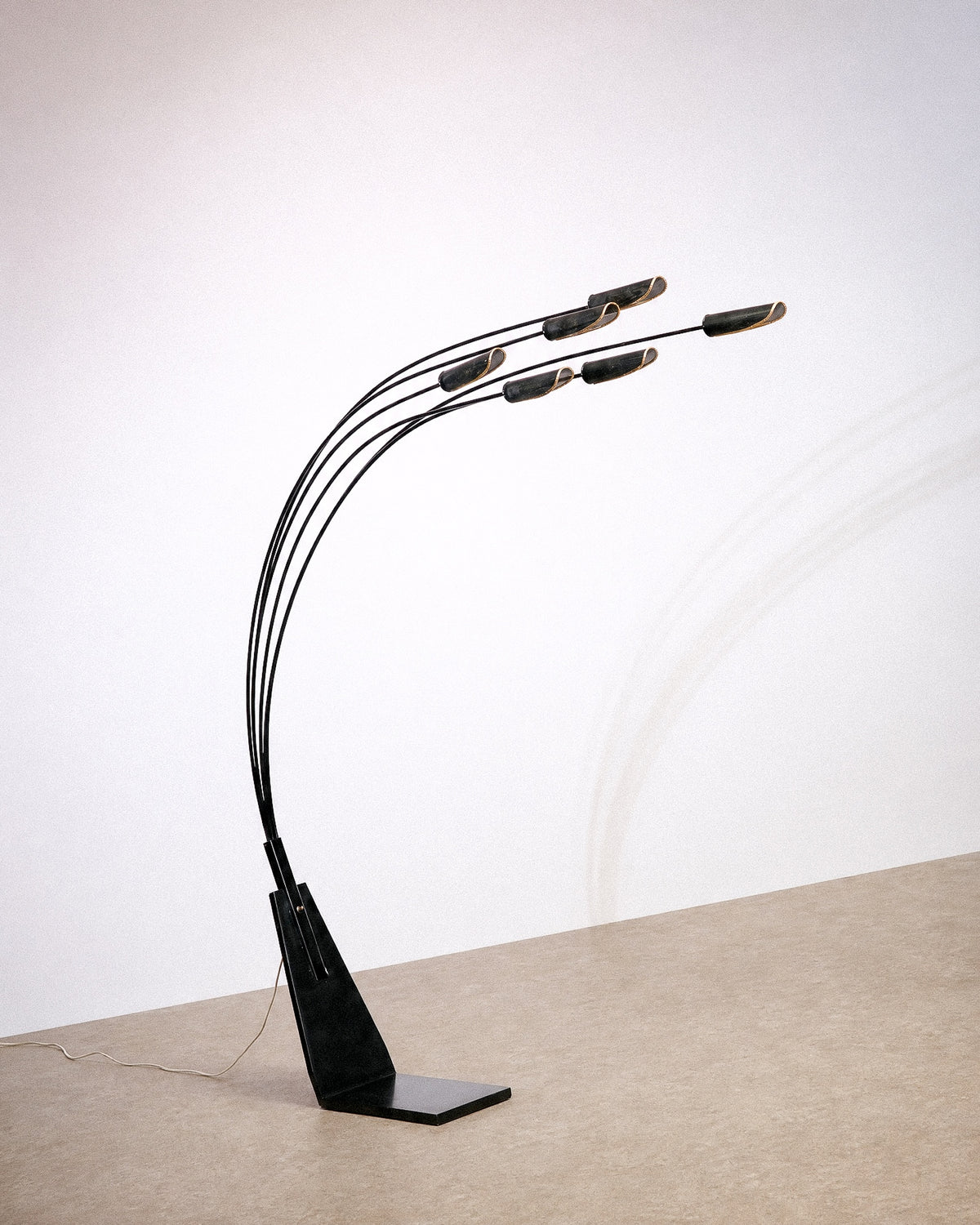 Full side view of the black 6-light floor lamp showing its curved arms and triangular base.