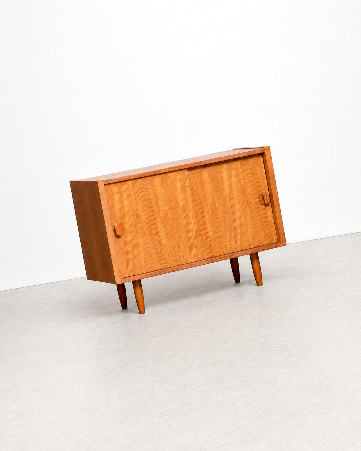 Side angle view of the teak cabinet against a plain white background, showing its tapered legs.