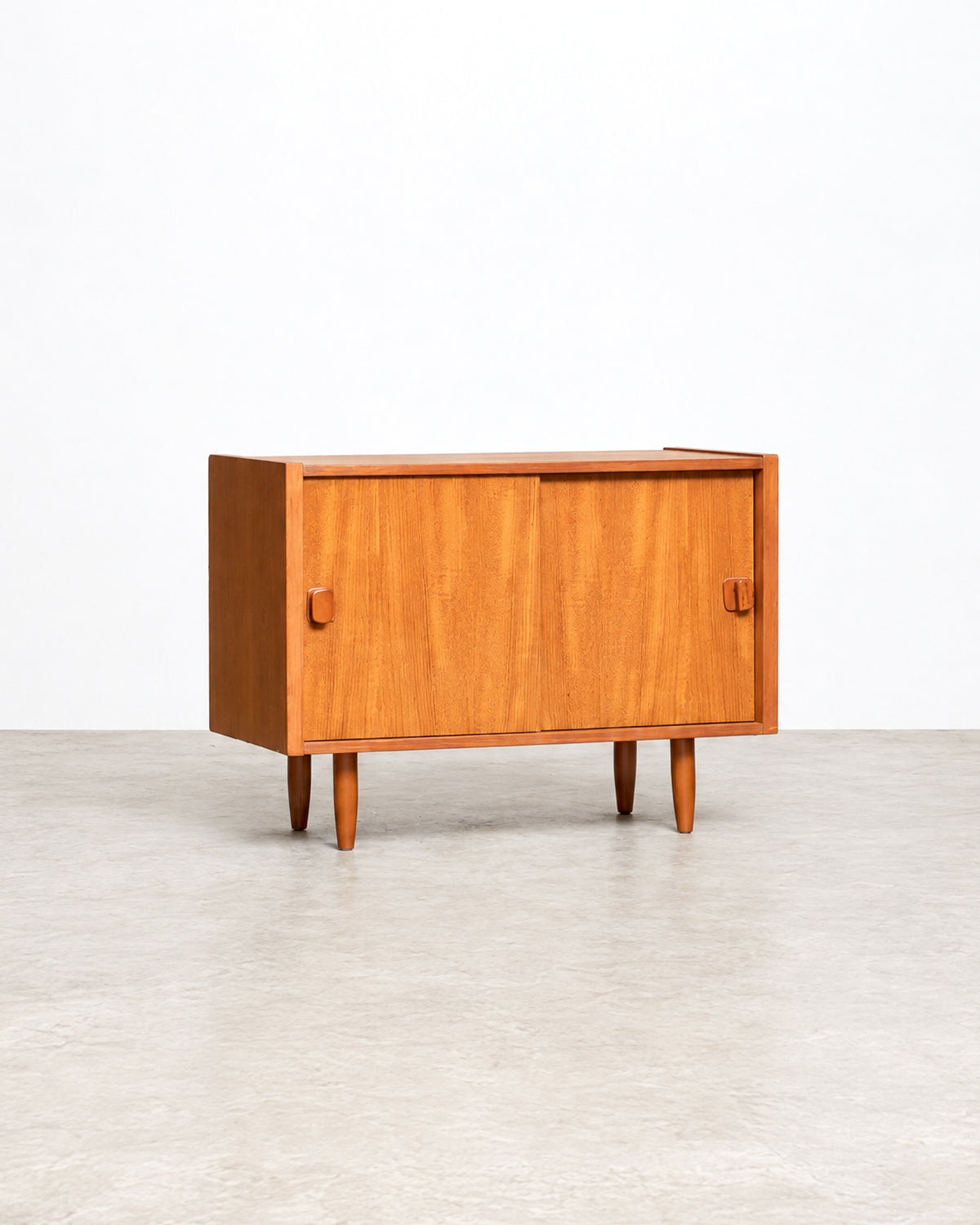 Detail view of the tapered wood legs supporting the teak cabinet.