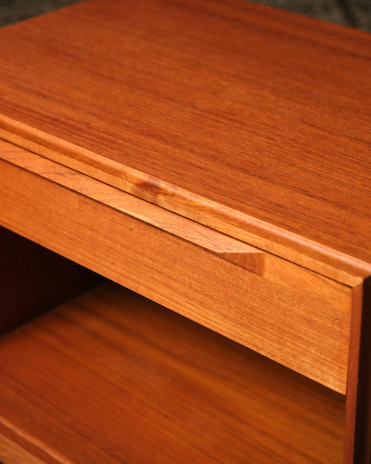 Close-up of the sculpted drawer pull and open shelf below