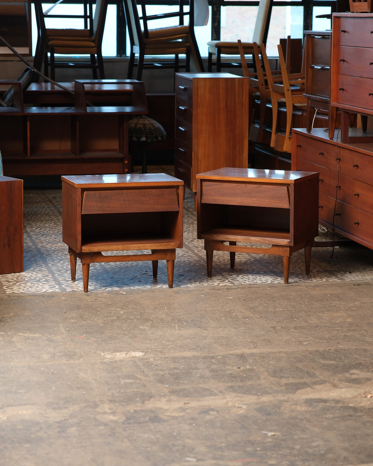 Pair of matching mid-century modern dark walnut nightstands shown together in a warehouse setting.