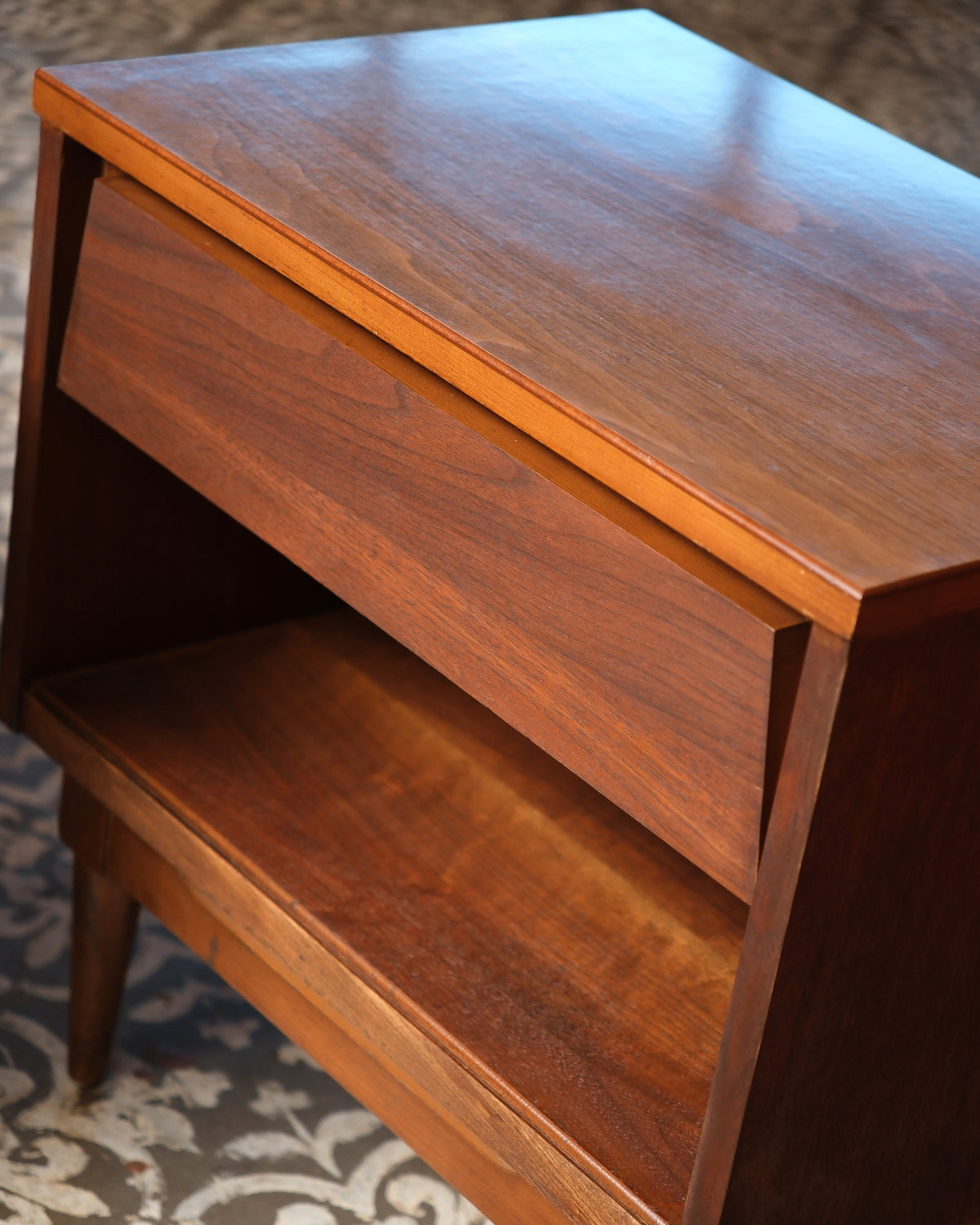 Close-up of the drawer front, tabletop grain, and joinery detail on the dark walnut nightstand.