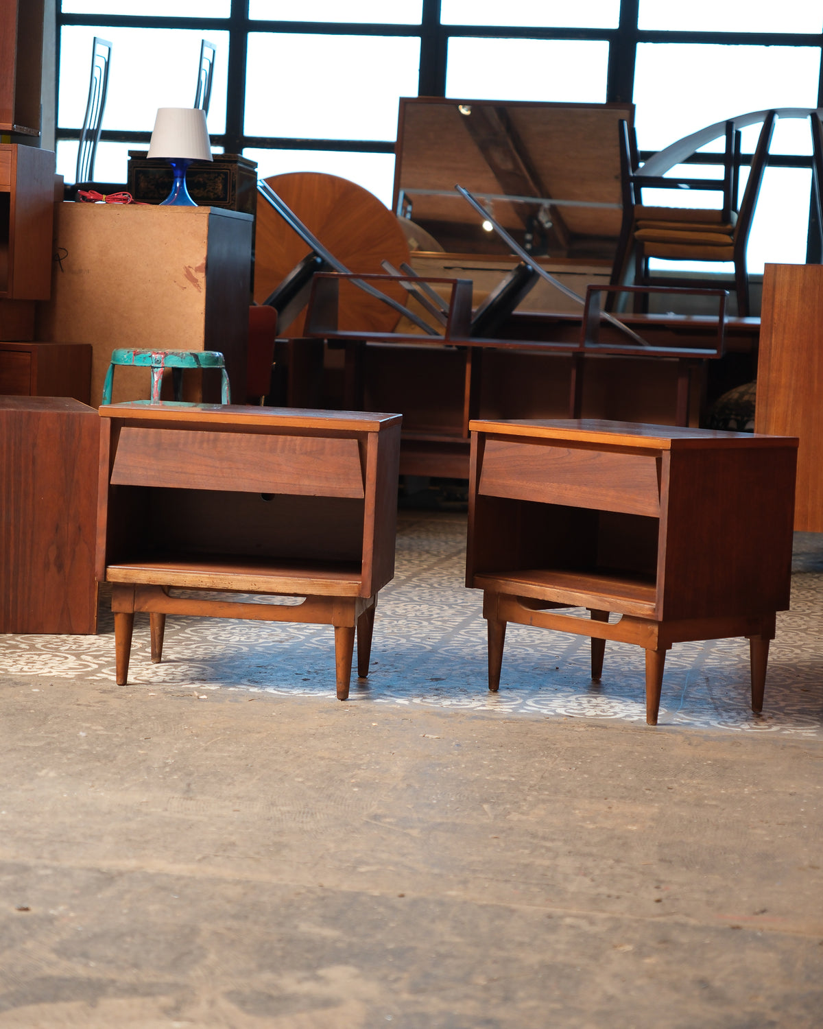 Front view of the pair of dark walnut nightstands side by side against a warehouse backdrop.
