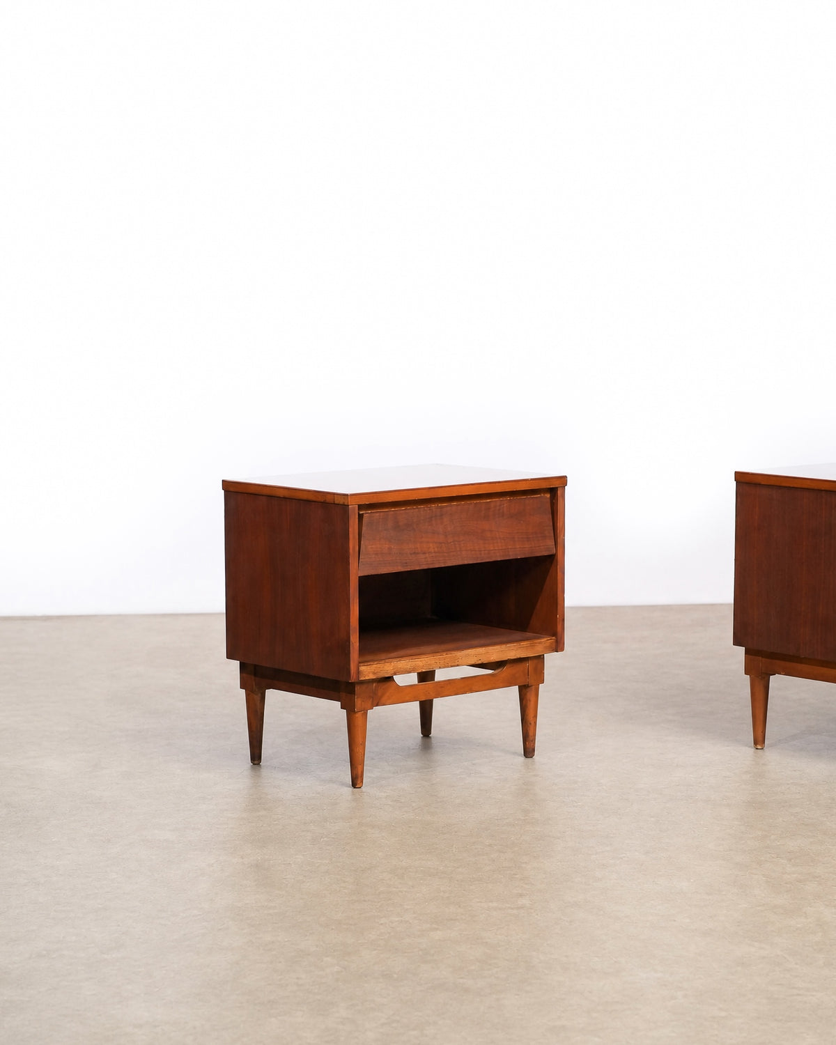 Side angle of one dark walnut nightstand with the second nightstand partially visible beside it.