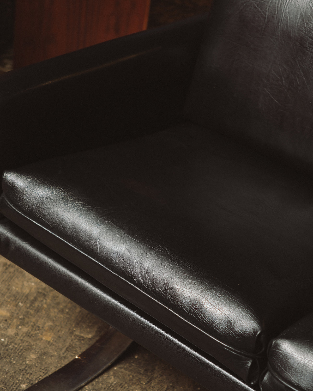 Detail view of the leather seat cushion and armrest from above, showing grain and wear.