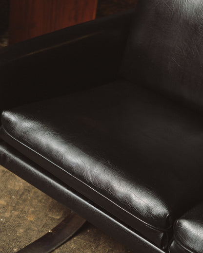 Detail view of the leather seat cushion and armrest from above, showing grain and wear.