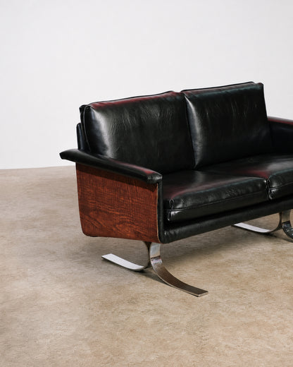 Side view of the sofa highlighting the curved wood panel and sculptural chrome leg.