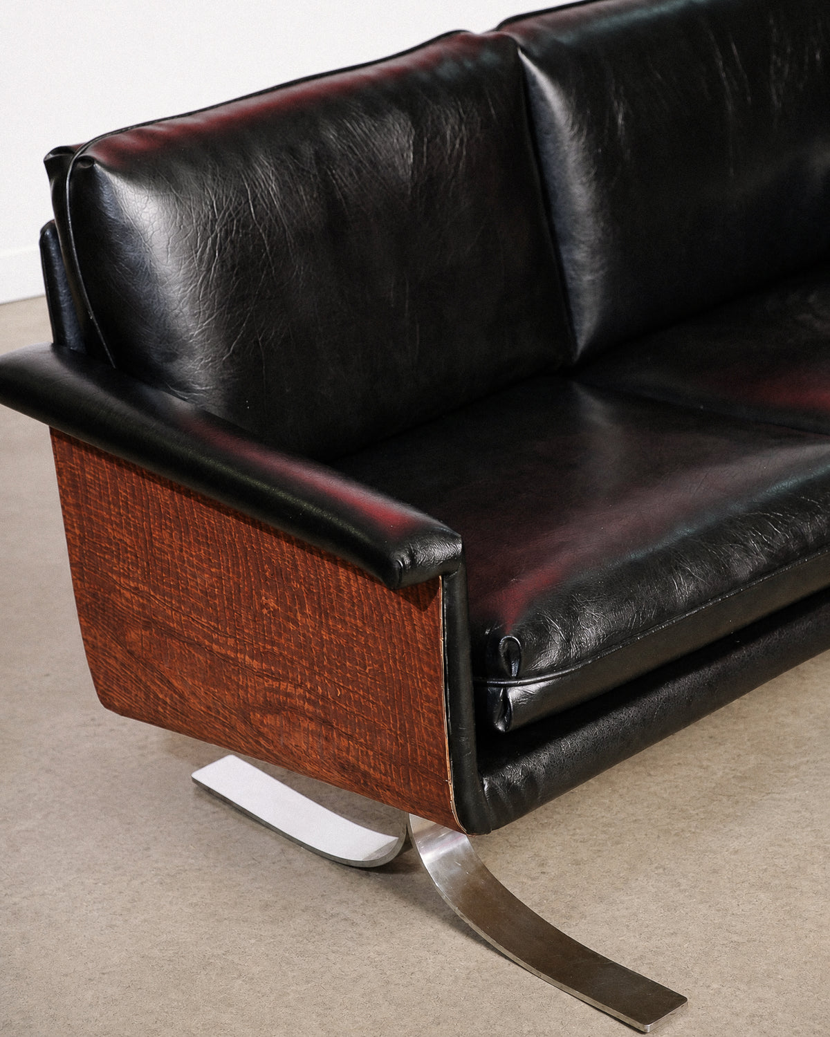 Close-up of the chrome leg and wood panel joint showing craftsmanship and finish.