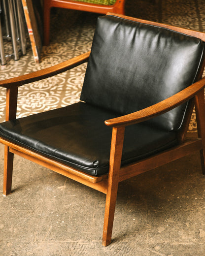 Front view of the lounge chair showing the open arm design and black vinyl upholstery.
