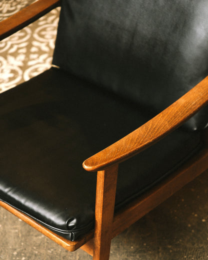 Detail of the armrest and seat cushion showing the wood joinery and vinyl texture.