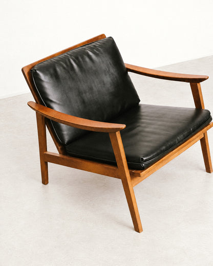 Side profile of the lounge chair showing the tapered legs and angled backrest.