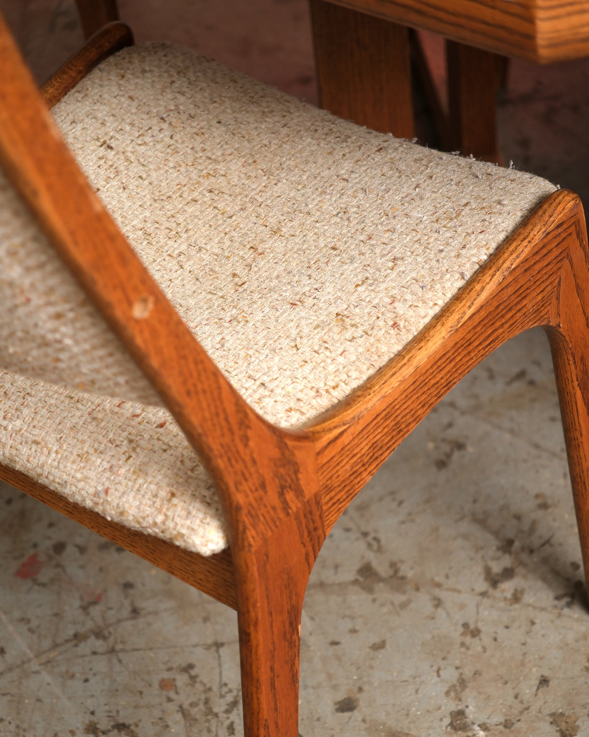 Close-up detail of a dining chair's tapered oak frame and tweed upholstered seat and back.
