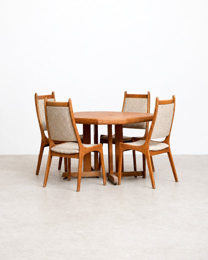 Mid-century modern oak extendable dining table with four upholstered chairs, front view.