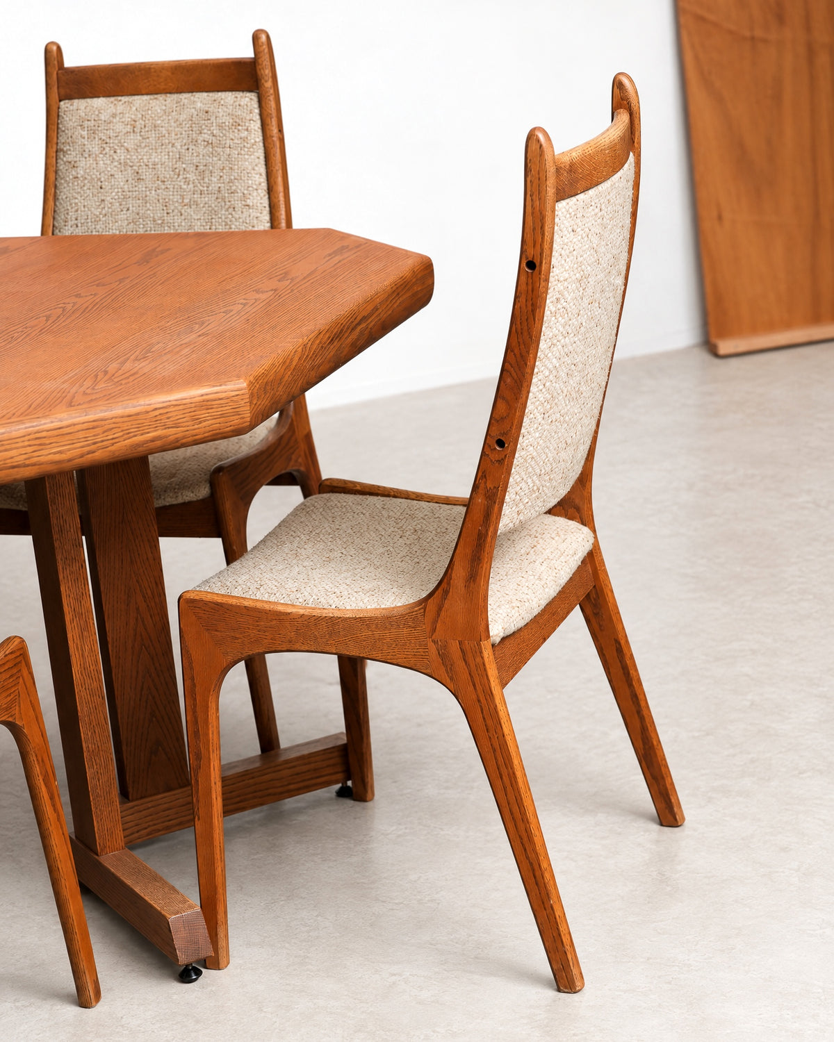 Angled view of a dining chair beside the table, showing the pedestal base and leg joinery.