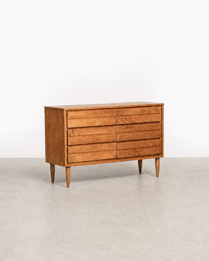Wooden dresser with multiple drawers on a plain background