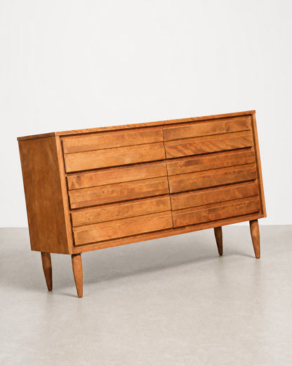 Wooden dresser with multiple drawers on a plain background