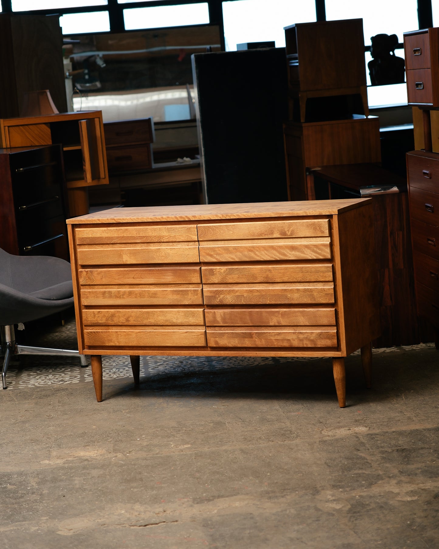 Wooden dresser in a storage or warehouse setting with other furniture items.