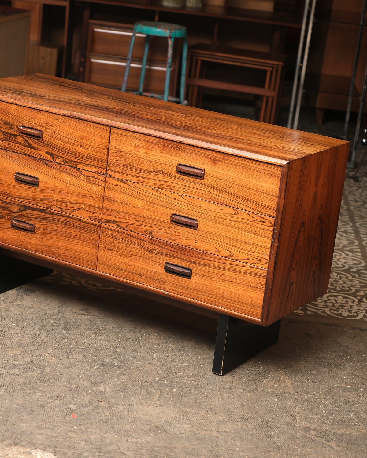 Close angled view of the rosewood dresser showing drawer fronts, wood pulls, and top corner joinery.