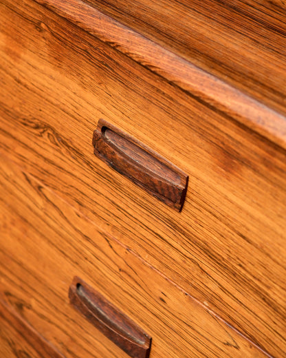 Close-up detail of a sculpted wood drawer pull and the natural rosewood grain pattern.