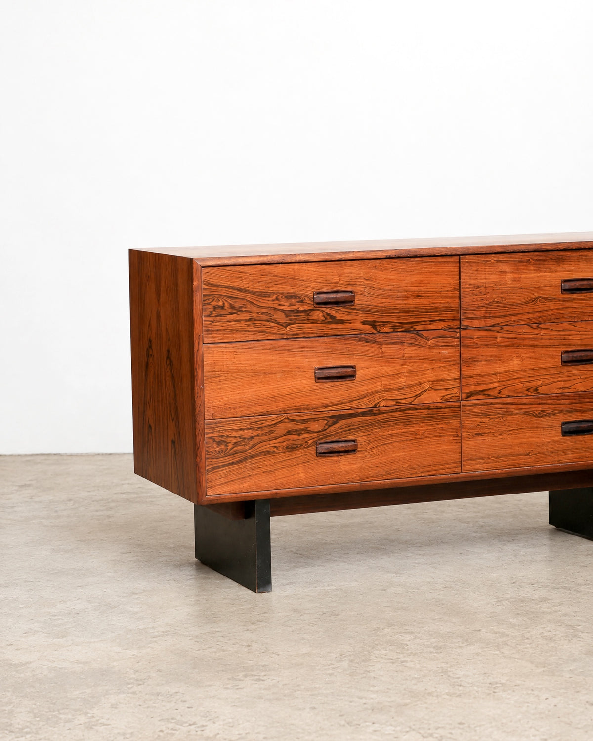 Low angled view of the dresser's front corner, showing drawer stack and metal leg design.